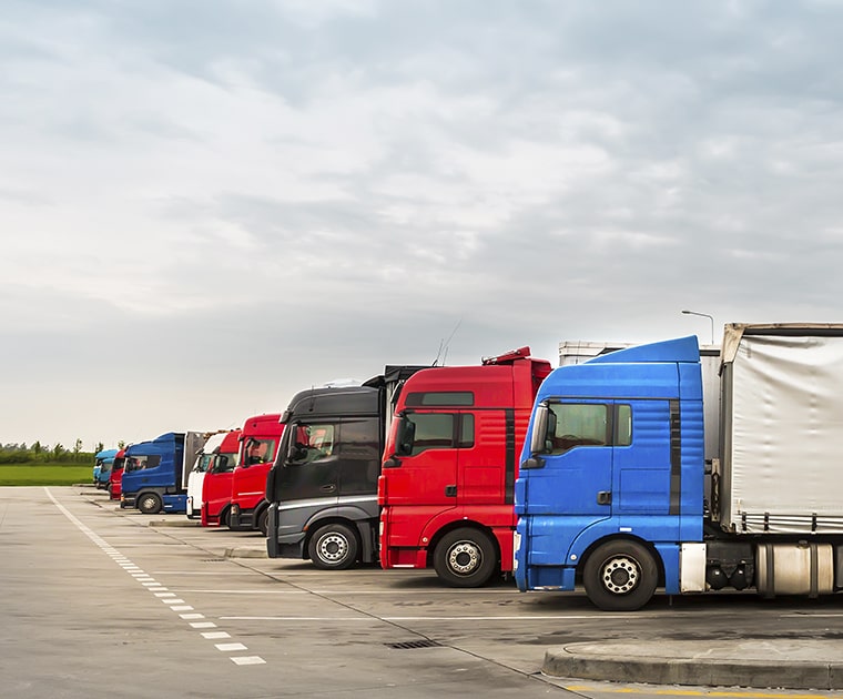 Vários caminhões estacionados lado a lado, representando o seguro de frota para todos os veículos da empresa.